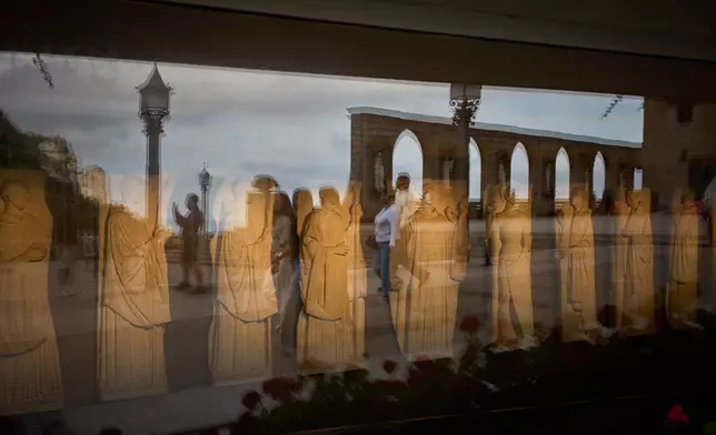Tourists are reflected in the glass of a museum on the main square of the Monastery of Montserrat near Barcelona, Spain, Friday, June 5, 2026. (AP Photo/Emilio Morenatti)