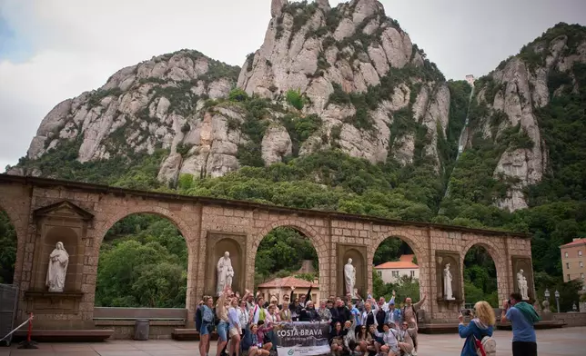 Tourists pose for a photo at the main square of the Monastery of Montserrat near Barcelona, Spain, Friday, June 5, 2026. (AP Photo/Emilio Morenatti)