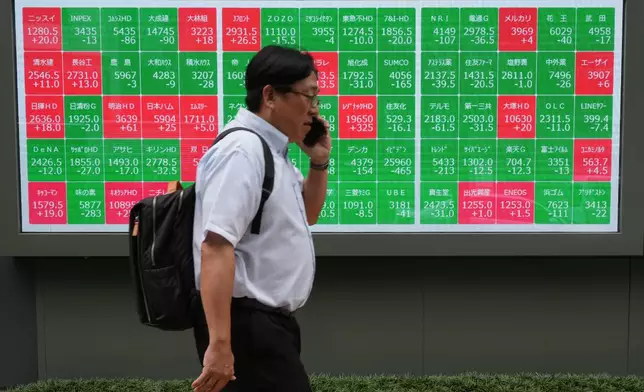 A man walks past a monitor showing stock prices of companies on the Tokyo Stock Exchange in Tokyo, Tuesday, June 23, 2026. (AP Photo/Hiro Komae)