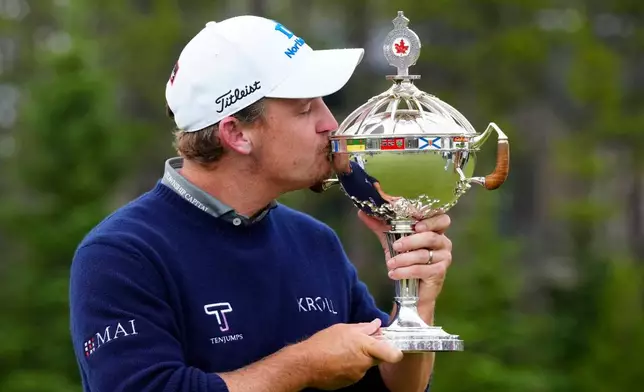 Bud Cauley, of the United States, kisses the trophy after winning the Canadian Open golf tournament in Caledon, Ontario, Sunday June 14, 2026. (Frank Gunn/The Canadian Press via AP)