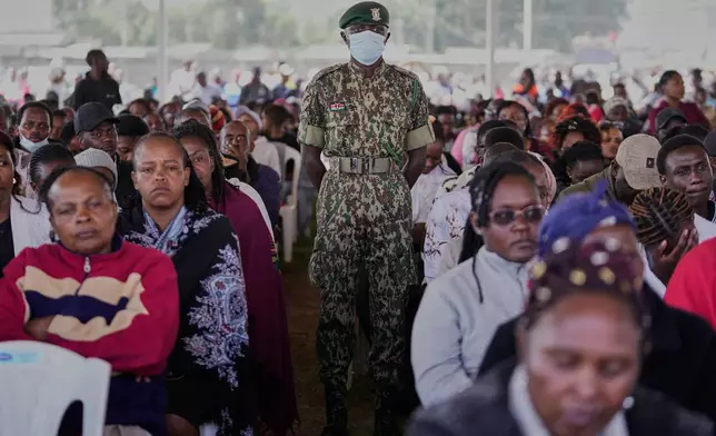 A member of Kenya's National Youth Service stands among mourners attending a memorial service for the 16 girls who died in the Utumishi Academy school fire at Gilgil Stadium, Nakuru County, Kenya, Friday, June 12, 2026. (AP Photo/Brian Inganga)