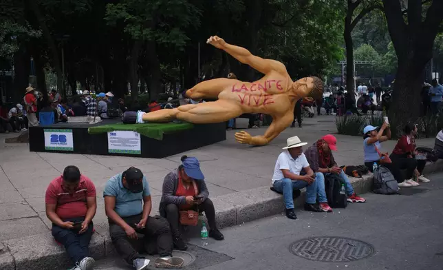 A World Cup statue, with graffiti that reads in Spanish, "The National Educational Workers Coordination lives" lies sideways during a teachers' protest for higher salaries sit in Mexico City, Tuesday, June 2, 2026. (AP Photo/Jon Orbach)