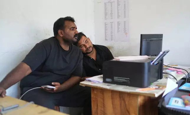 Safeer Mohammed Koorimannil, right, leans on the shoulder of his brother, Jouhar Babu, while working at their CM Fisheries office in Sulthan Bathery in the southern state of Kerala, India, Thursday, March 12, 2026. (AP Photo/Manish Swarup)