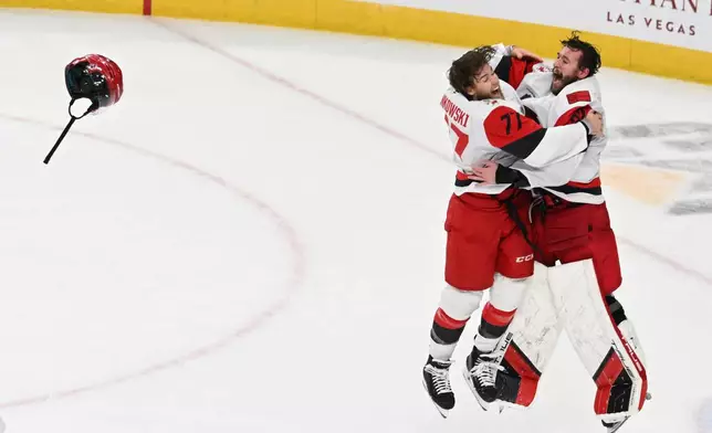 Carolina Hurricanes left wing Mark Jankowski (77) and goaltender Brandon Bussi (32) celebrate after a win over the Vegas Golden Knights in Game 6 of the NHL hockey Stanley Cup Final series, Sunday, June 14, 2026, in Las Vegas. (AP Photo/Candice Ward)