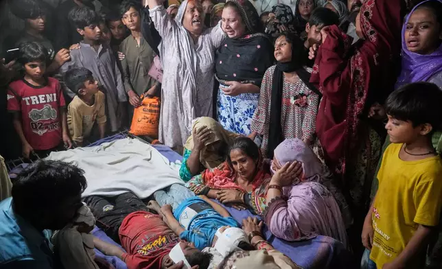 Women mourn next to the bodies of their children killed after the roof of a tutoring center under-construction collapsed, on the outskirts of Lahore, Pakistan, Tuesday, June 30, 2026. (AP Photo/K.M Chaudary)