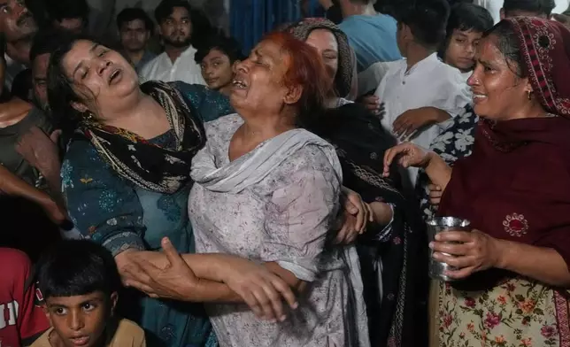 Women mourn over the death of their children killed after the roof of a tutoring center under-construction collapsed, on the outskirts of Lahore, Pakistan, Tuesday, June 30, 2026. (AP Photo/K.M Chaudary)