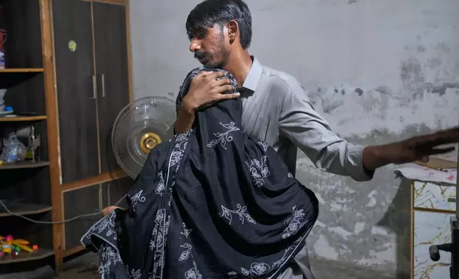 A man comforts a woman mourning over the death of her child, killed after the roof of a tutoring center under-construction collapsed, on the outskirts of Lahore, Pakistan, Tuesday, June 30, 2026. (AP Photo/K.M Chaudary)
