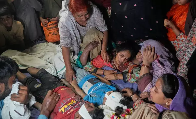 Women mourn next to the bodies of their children killed after the roof of a tutoring center under-construction collapsed, on the outskirts of Lahore, Pakistan, Tuesday, June 30, 2026. (AP Photo/K.M Chaudary)