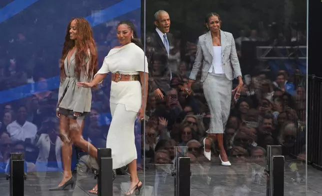 Former President Barack Obama, back center, and former first lady Michelle Obama, right, arrive on stage with their daughters, Sasha and Malia Obama, during the dedication ceremony for the Obama Presidential Center, Thursday, June 18, 2026, in Chicago. (AP Photo/Jeff Roberson)