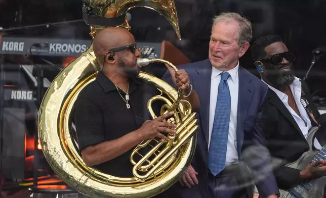Former President George W. Bush, right, on stage with members of The Roots during the dedication ceremony for the Obama Presidential Center, Thursday, June 18, 2026, in Chicago. (AP Photo/Jeff Roberson)