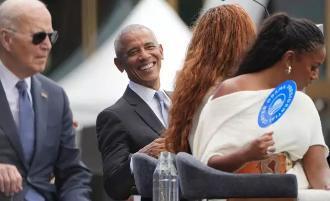Former President Barack Obama, center, smiles as he reacts to the musical performance by Stevie Wonder, also with Obama are from l-r., former President Joe Biden, and Obama's daughters Malia and Sasha during the dedication ceremony for the Obama Presidential Center, Thursday, June 18, 2026, in Chicago. (AP Photo/Alex Brandon)