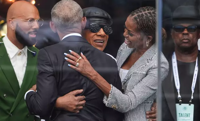 Former President Barack Obama, left, and former first lady Michelle Obama, right, embrace Stevie Wonder during the dedication ceremony for the Obama Presidential Center, Thursday, June 18, 2026, in Chicago. (AP Photo/Jeff Roberson)