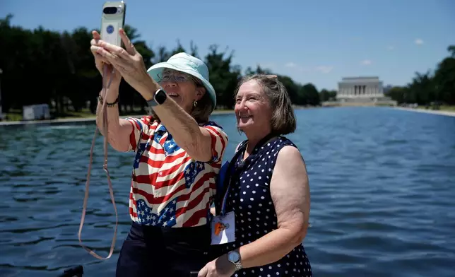 Visitors take a selfie at the Lincoln Memorial Reflecting Pool, Wednesday, June 24, 2026, in Washington. (AP Photo/Rahmat Gul)