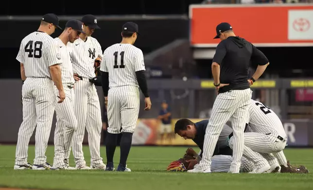 New York Yankees players and staff check on Jazz Chisholm Jr., bottom right, during the fourth inning of a baseball game against the Detroit Tigers, Monday, June 29, 2026, in New York. (AP Photo/Pamela Smith)
