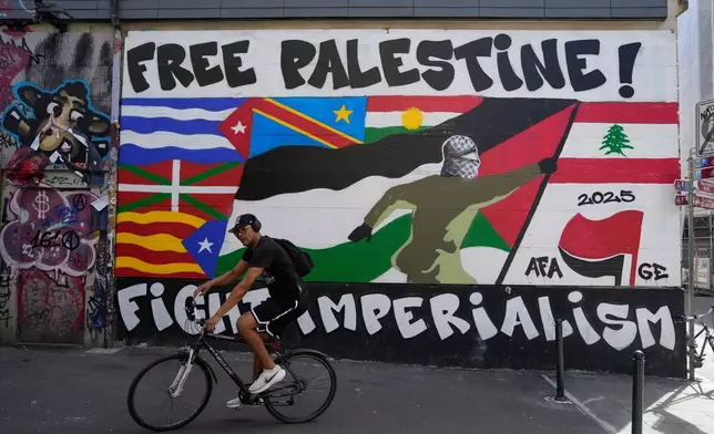 A man rides his bicycle in front of a mural, ahead of expected protests for the G7 summit, in Geneva, Switzerland, Monday, June 8, 2026. (AP Photo/Baz Ratner)