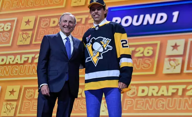 Liam Ruck, right, stands with NHL Commissioner Gary Bettman after being drafted by the Pittsburgh Penguins during the NHL hockey draft Friday, June 26, 2026, in Buffalo, N.Y. (AP Photo/Adrian Kraus)