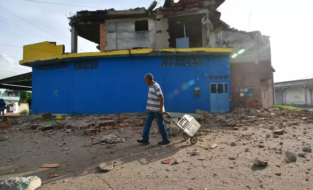 A man walks past a damaged home in Moron, near the epicenter of two earthquakes that struck Venezuela the day before, Thursday, June 25, 2026. (AP Photo/Jacinto Oliveros)