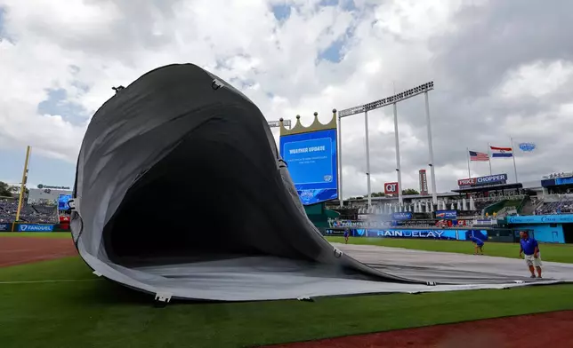Members of the Kansas City Royals grounds crew remove the infield tarp after a more than two-hour rain delay before a baseball game against the Texas Rangers in Kansas City, Mo., Thursday, June 11, 2026. (AP Photo/Colin E. Braley)