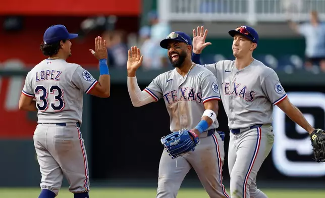 Texas Rangers' Nicky Lopez (33) Ezequiel Duran, center, and Wyatt Langford, right, celebrate at the end of a baseball game against the Kansas City Royals in Kansas City, Mo., Thursday, June 11, 2026. (AP Photo/Colin E. Braley)