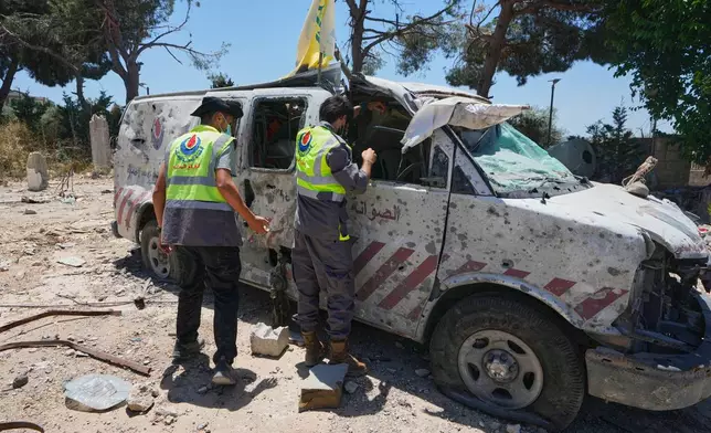 Rescue workers inspect a damaged ambulance belonging to Hezbollah's health unit that was hit in a previous Israeli airstrike in the southern village of Souaneh, Lebanon, Tuesday, June 16, 2026. (AP Photo/Mohammed Zaatari)