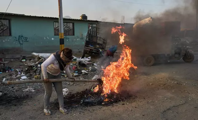 Giovana Rosas burns cables to extract copper for sale in the El Milagro district of Trujillo, Peru, Tuesday, May 26, 2026. (AP Photo/Rodrigo Abd)