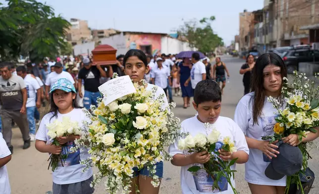 Children carry flowers during the funeral of Gian Marco Garcia, who was killed by a hitman in El Porvenir, a district of Trujillo, Peru, Monday, May 25, 2026. (AP Photo/Rodrigo Abd)