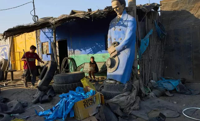 A man works at a tire shop adorned with a statue of Peruvian poet Cesar Vallejo in the El Milagro district of Trujillo, Peru, Sunday, May 16, 2026. (AP Photo/Rodrigo Abd)