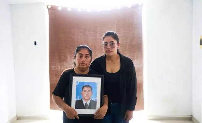 Diane Aguilar, left, and her daughter Perla pose for a photograph with a portrait of Aguilar's husband, Oscar Lavado, who was killed by hitmen on motorbike as he was driving his car weeks earlier, in Trujillo, Peru, Sunday, May 17, 2026. (AP Photo/Rodrigo Abd)