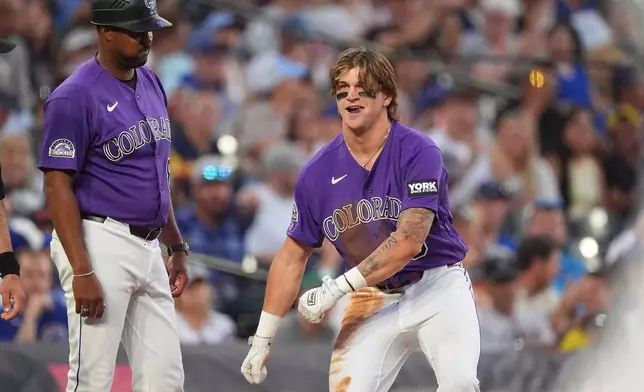 Colorado Rockies third base coach Andy Gonzalez, left, watches as Cole Carrigg celebrates after reaching third base on a triple—his first hit in the Major Leagues—off Chicago Cubs starting pitcher Colin Rea in the fifth inning of a baseball game Tuesday, June 9, 2026, in Denver. (AP Photo/David Zalubowski)