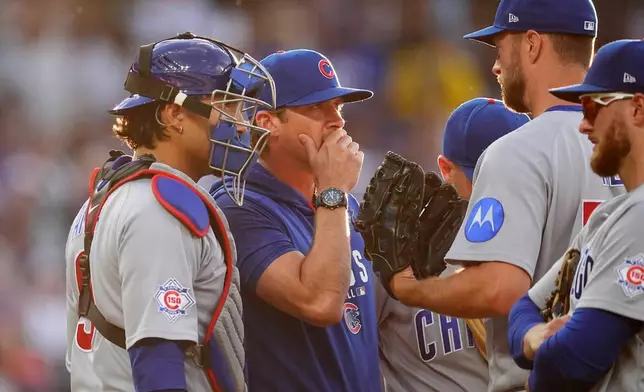 Chicago Cubs pitching coach Tommy Hottovy, center, confers with catcher Miguel Amaya, left, and starting pitcher Colin Rea after he walked Colorado Rockies' Kyle Karros to load the bases in the third inning of a baseball game, Tuesday, June 9, 2026, in Denver. (AP Photo/David Zalubowski)