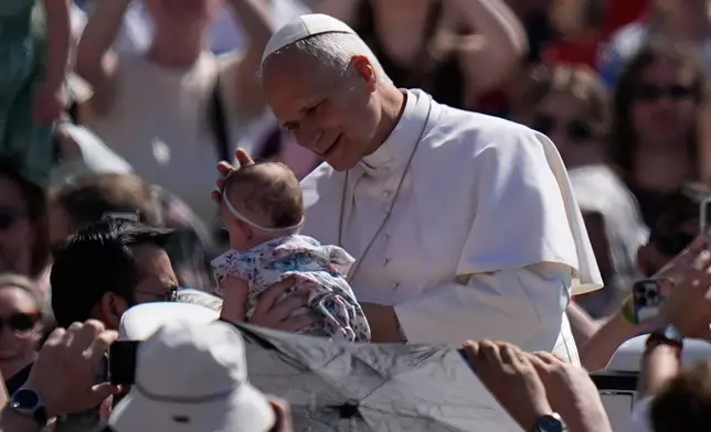 Pope Leo XIV blesses a new born as he arrives for his weekly general audience in St. Peter's Square at The Vatican, Wednesday, May 27, 2026. (AP Photo/Alessandra Tarantino)