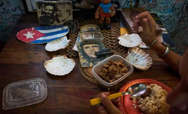 A souvenir shop worker eats next to images of Che Guevara, Fidel Castro, and Ernest Hemingway in Havana, Tuesday, June 2, 2026. (AP Photo/Ramon Espinosa)