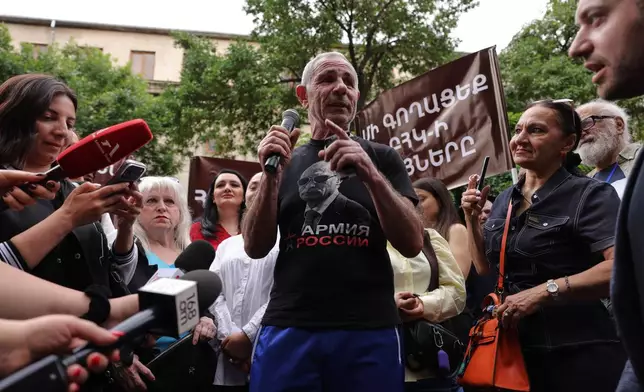 A man wearing in t-shirt with an image of Russian President Vladimir Putin and words reading "Army of Russia" gestures speaking to demonstrators of opposition parties gathered in protest of the results of the parliamentary elections in Yerevan, Armenia, Sunday, June 14, 2026. (AP Photo/Anthony Pizzoferrato)