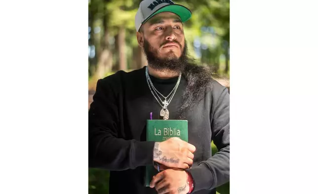 Gabriel Martinez Garcia, 30, holds a Bible close to his chest as tattoos of his parents are visible on his wrists, in Tenino, Wash., on Sunday, June 14, 2026. (AP Photo/Akash Pamarthy)