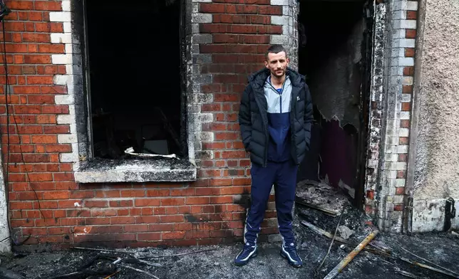 Jamie Corrie stands beside his burnt out house after rioting broke out late Tuesday, in east Belfast, Northern Ireland, Wednesday, June 10, 2026, following a stabbing incident. (AP Photo/Peter Morrison)