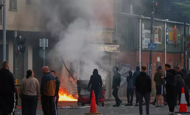 A building is set light to by protesters in central Belfast following a stabbing incident in Belfast, Tuesday, June 9, 2026. (AP Photo/Peter Morrison)
