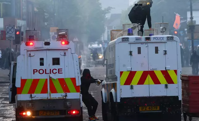 Police vehicles come under attack from protesters following a stabbing incident in Belfast, Tuesday, June 9, 2026. (AP Photo/Peter Morrison)