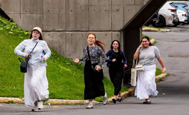 People run out of a shopping center near the scene of a shooting in Montreal on Monday, June 22, 2026. (Christopher Katsarov/The Canadian Press via AP)