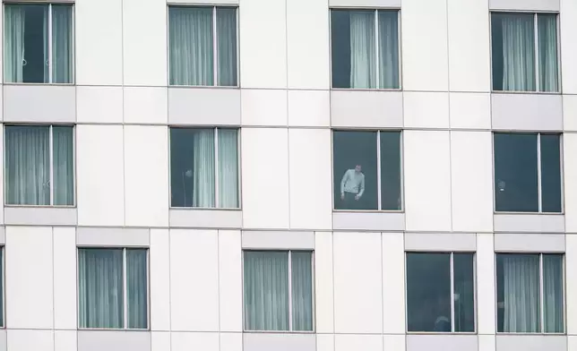 A person looks out of a hotel window at the scene of a shooting in Montreal on Monday, June 22, 2026. (Christopher Katsarov/The Canadian Press via AP)