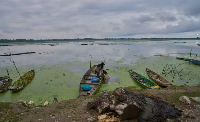 A Kashmiri woman cleans a blanket in algae-filled water on the banks of Wular Lake in Bandipor, northeast of Srinagar, Indian controlled Kashmir, Tuesday, May 5, 2026. (AP Photo/Dar Yasin)