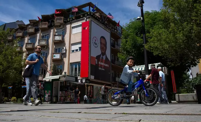People walk past a giant election poster of acting prime minister Albin Kurti in capital Pristina, Kosovo, Friday, June 5, 2026, ahead of snap parliamentary elections on June 7. (AP Photo/Visar Kryeziu)