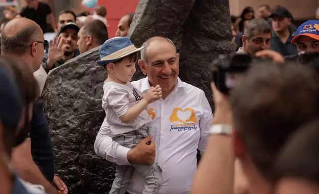 Armenian Prime Minister Nikol Pashinyan holds a child as he walks on Northern Avenue in Yerevan, Armenia, Monday, June 1, 2026, during public celebrations marking International Children's Day. (AP Photo/Anthony Pizzoferrato)