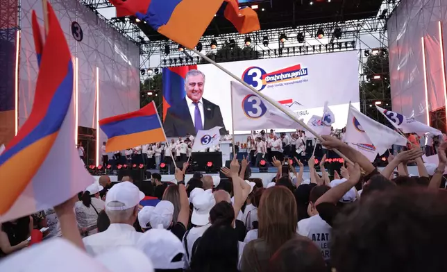 Supporters of Russian-Armenian tycoon Samvel Karapetyan, on screen, attend a rally with Armenian national flags against incumbent Prime Minister Nikol Pashinyan at Republic Square in Yerevan, Armenia, Wednesday, June 3, 2026, as Karapetyan, who heads the Strong Armenia party, has faced criminal charges that he rejected as politically driven and campaigned from under house arrest. (AP Photo/Anthony Pizzoferrato)
