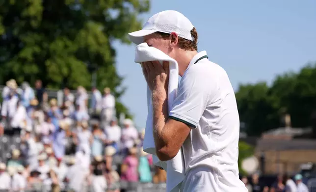Jannik Sinner of Italy uses a towel to wipe his face during a tennis exhibition match against Cameron Norrie of Great Britain at the Hurlingham Tennis Club in London, Wednesday, June 24, 2026.(AP Photo/Kirsty Wigglesworth)