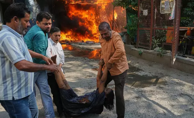 Local people rescue a foreign national from a hotel fire in New Delhi, India, Wednesday, June 3, 2026. (AP Photo/Manish Swarup)