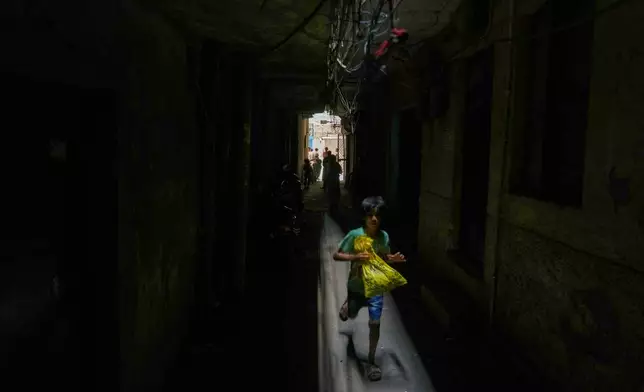 A boy runs through a dark alley next to a restaurant and hotel building that caught fire early this morning in New Delhi, India, Wednesday, June 3, 2026. (AP Photo/Manish Swarup)