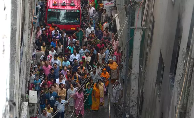 Locals and bystanders watch a hotel fire as firefighters work to douse the flames in New Delhi, India, Wednesday, June 3, 2026. (AP Photo/Manish Swarup)