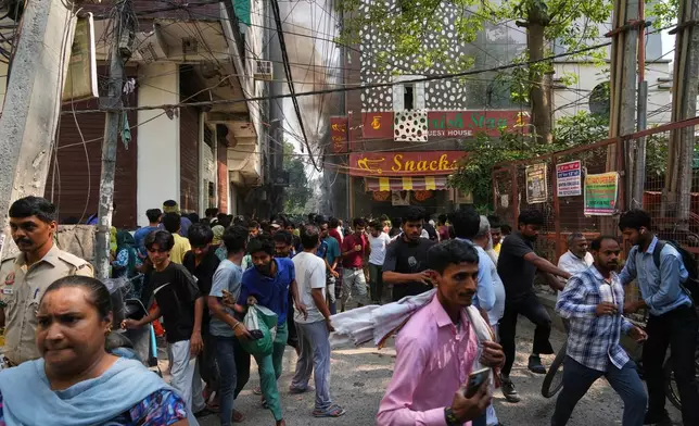 Locals and bystanders run for cover as a hotel fire spreads following electrical sparks in New Delhi, India, Wednesday, June 3, 2026. (AP Photo/Manish Swarup)