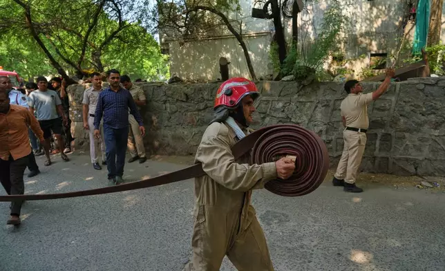 A firefighter runs with a hose toward a hotel fire in New Delhi, India, Wednesday, June 3, 2026. (AP Photo/Manish Swarup)