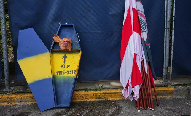 A cardboard coffin decorated with Boca Juniors' colors sits next to River Plate flags next to a highway prior to an Argentine league soccer match in Buenos Aires, Argentina, Sunday, April 19, 2026. (AP Photo/Rodrigo Abd)
